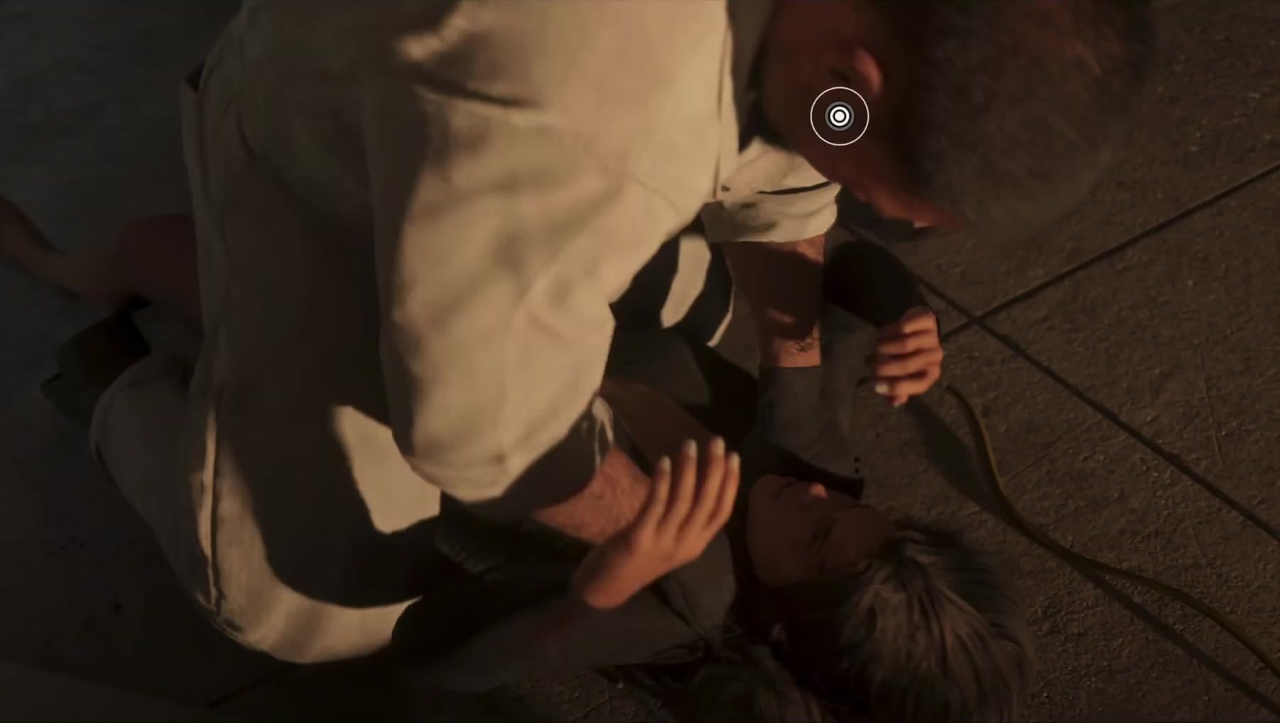The reticle holds on the raider pinning the woman as she begins to fight back